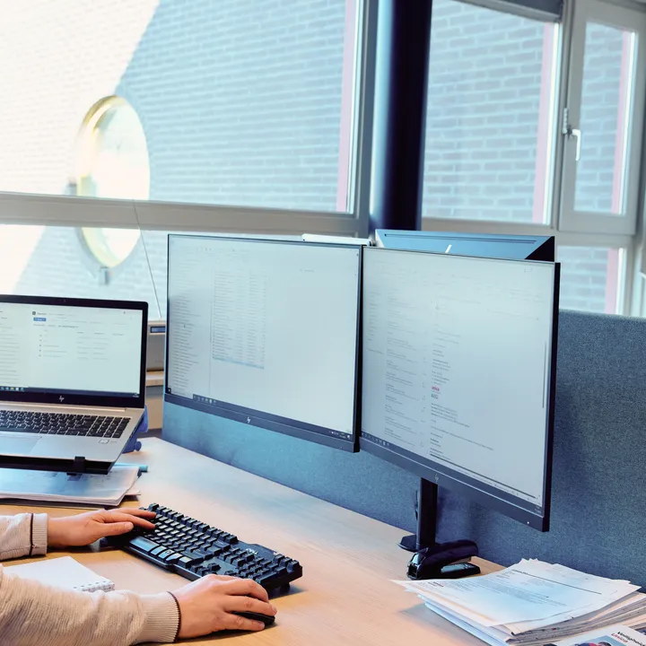 Medewerker van Unica werkt achter de computer met verschillende programma's open