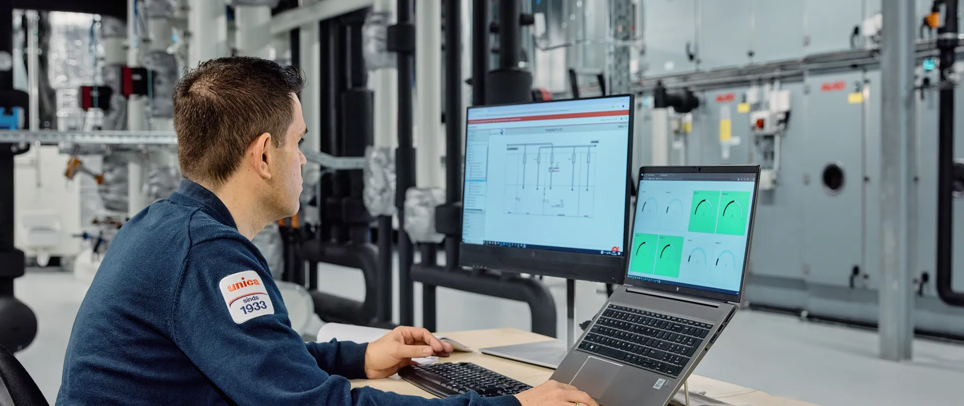 Medewerker van Unica zit achter de computer in een technische ruimte en monitort installaties