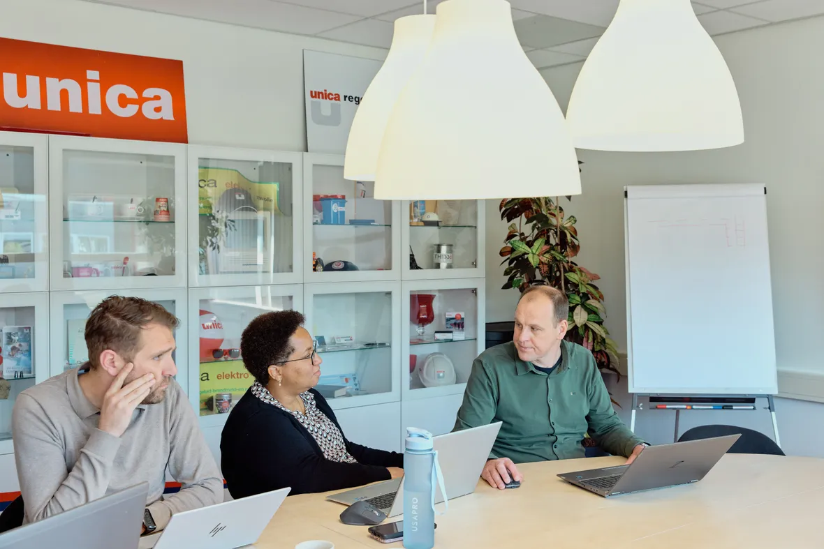 Drie medewerkers van Unica zitten aan tafel tijdens een  overleg