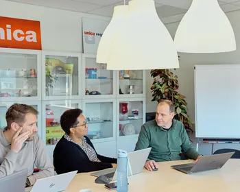 Drie medewerkers van Unica zitten aan tafel tijdens een  overleg