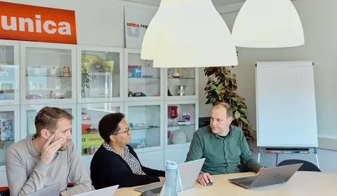 Drie medewerkers van Unica zitten aan tafel tijdens een  overleg