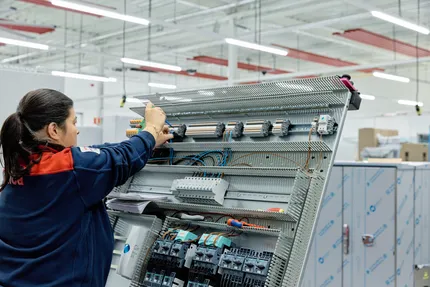 Medewerker van Unica werkt aan regelkast met schroevendraaier