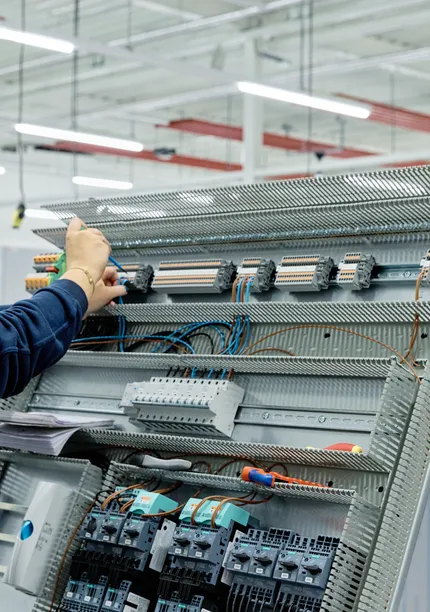 Medewerker van Unica werkt aan regelkast met schroevendraaier
