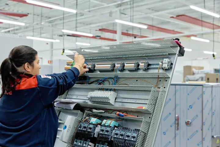 Medewerker van Unica werkt aan regelkast met schroevendraaier