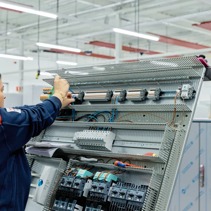Medewerker van Unica werkt aan regelkast met schroevendraaier