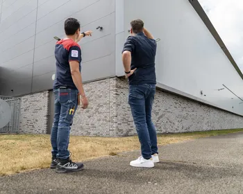 Twee mannen kijken naar een camera op een pand