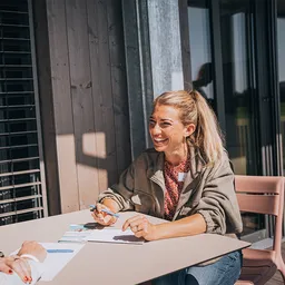 Zwei Rehaberaterinnen aus dem Hegau-Jugendwerk sitzen zum Austausch an einem Tisch in der Sonne und lachen sich an
