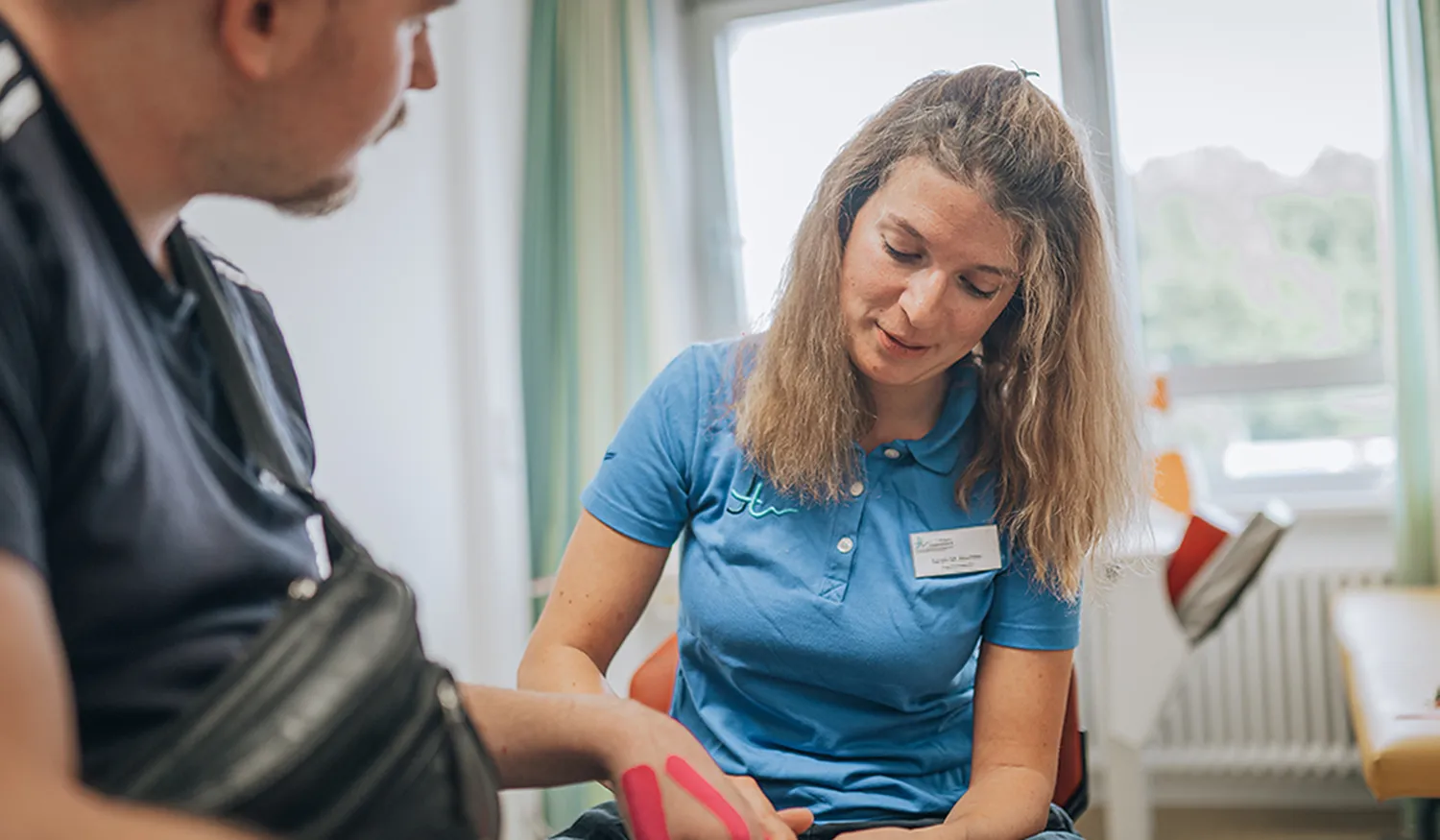 Therapeutin trainiert mit einem jungen Rehabilitanden die Funktion einer getapten Hand im Hegau-Jugendwerk Gailingen