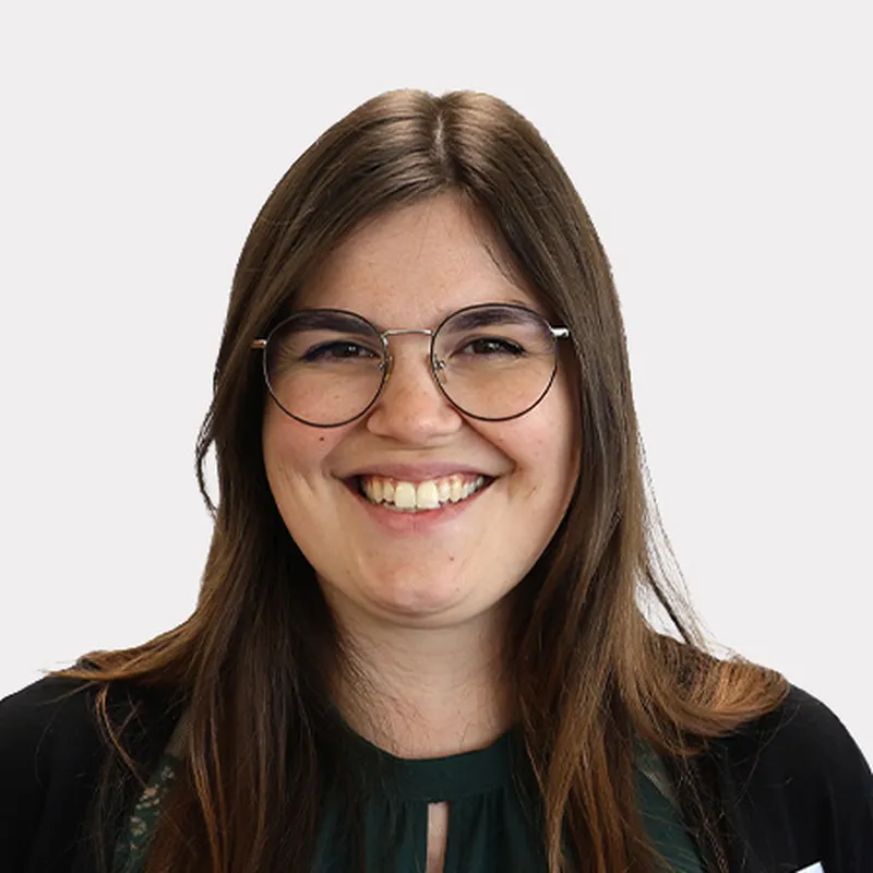 Eine lächelnde Frau mit langen braunen Haaren, Brille und dunkelgrünem Oberteil.  Sie ist eine Mitarbeiterin Fundraising im Hegau-Jugendwerk Gailingen.
