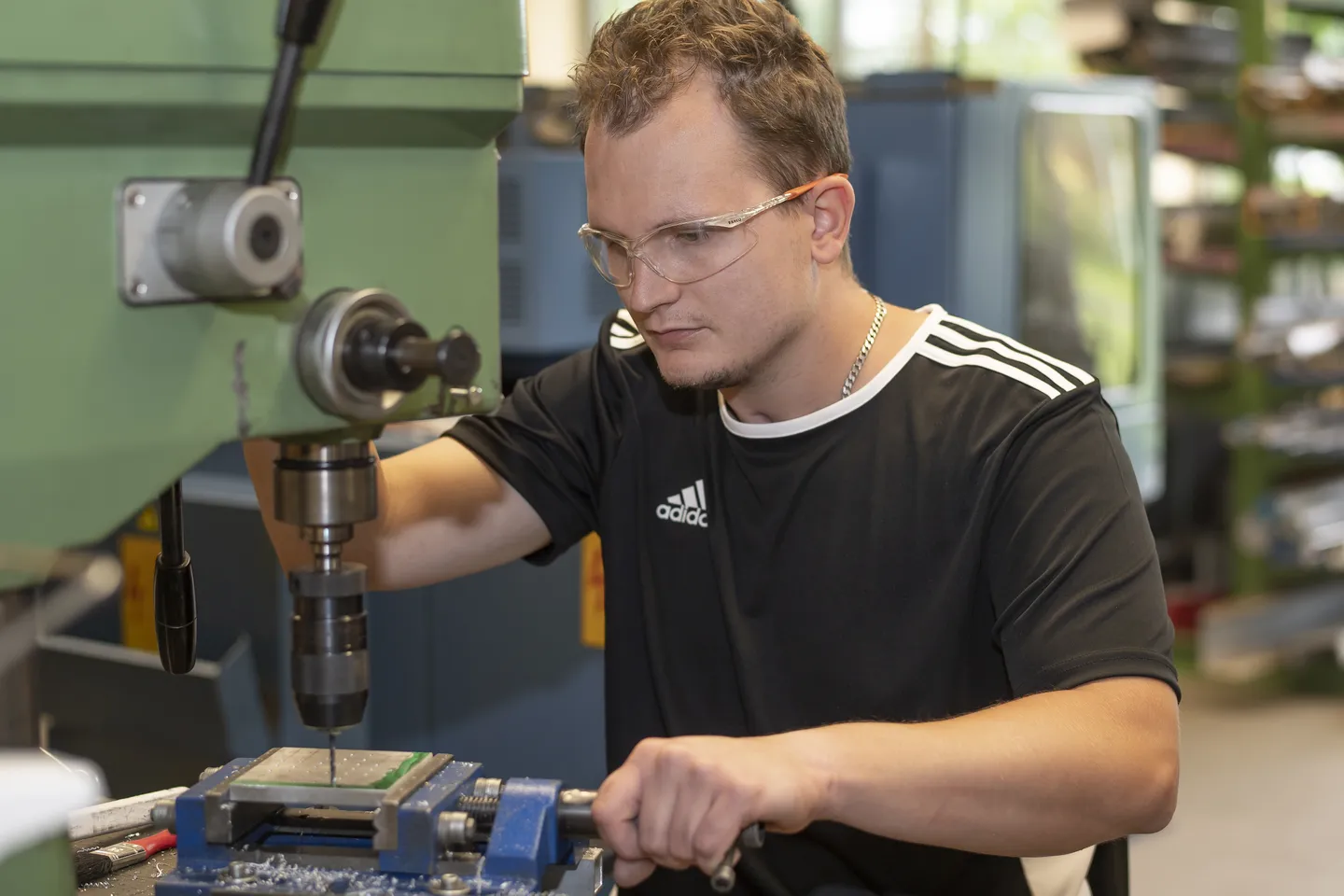 Junger Rehabilitand arbeitet an einer Bohrmaschine im Berufsbildungsbereich Metalltechnik der Berufstherapie im Hegau-Jugendwerk Gailingen.