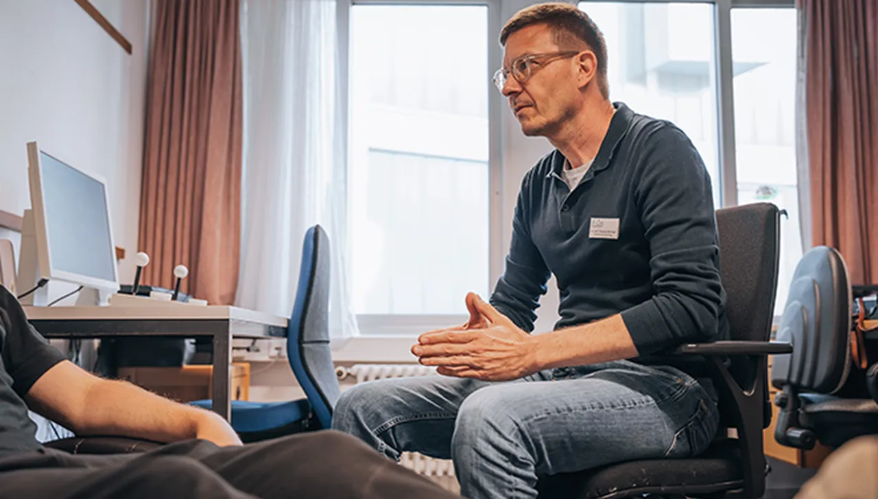 Psychologe im Hegau-Jugendwerk bei einer therapeutischen Sitzung, Patient liegt auf einer Liege, ohne sichtbares Gesicht.