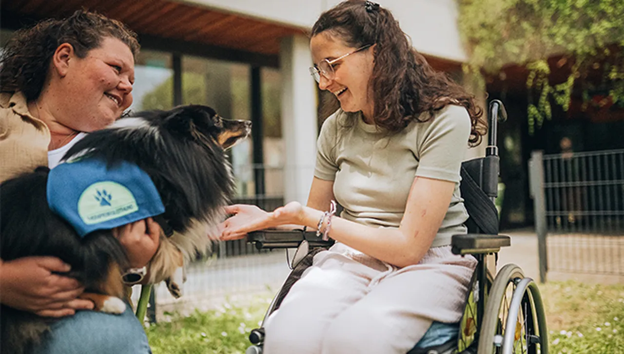 Sozialpädagogin mit Therapiehund im Hegau-Jugendwerk bei der tiergestützten Pädagogik mit einer Rehabilitandin im Rollstuhl.
