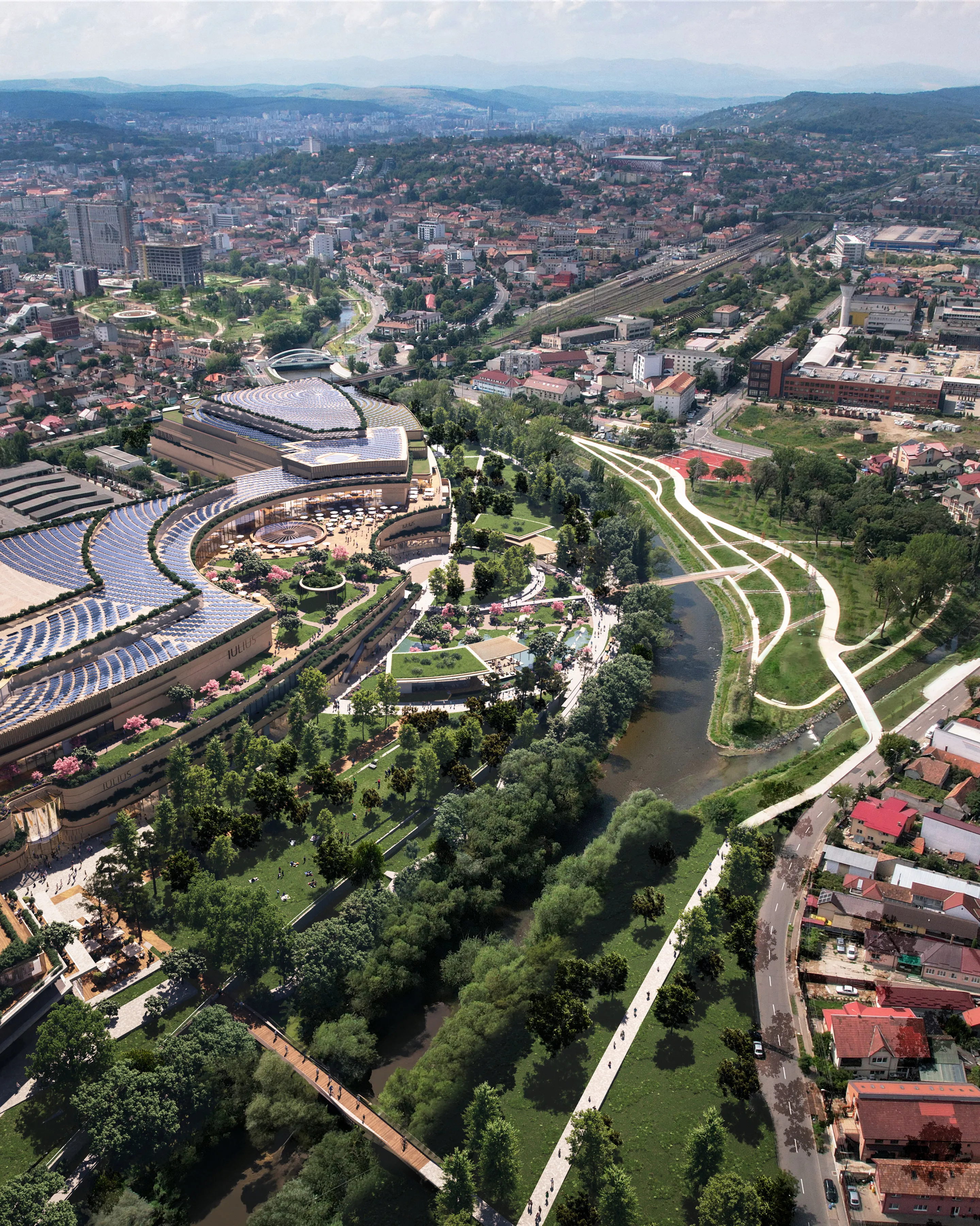 Aerial view of a cityscape with modern architecture, green parks, winding pathways, and a river, surrounded by residential and urban areas.