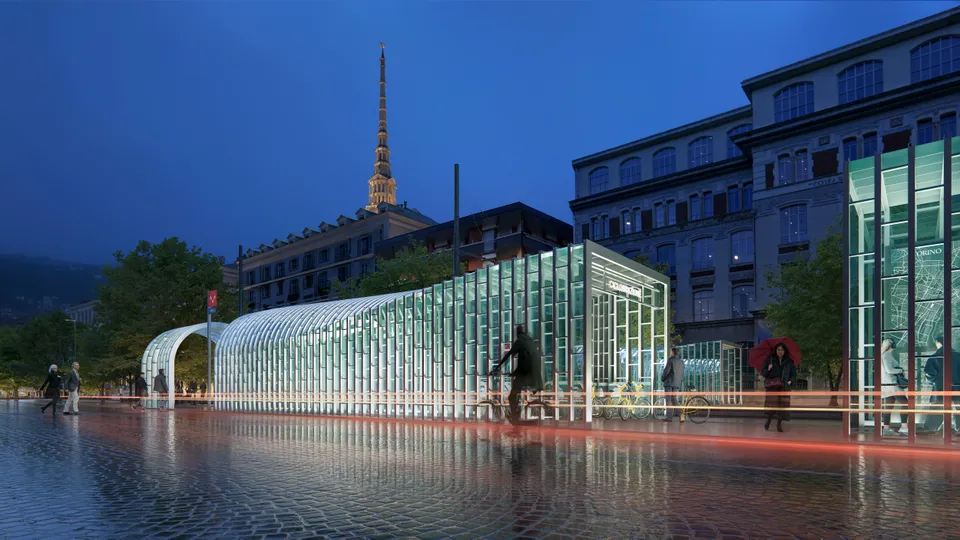 Modern glass structures lit up at night in a city square, with blurred motion of people walking, and a tower visible in the background.