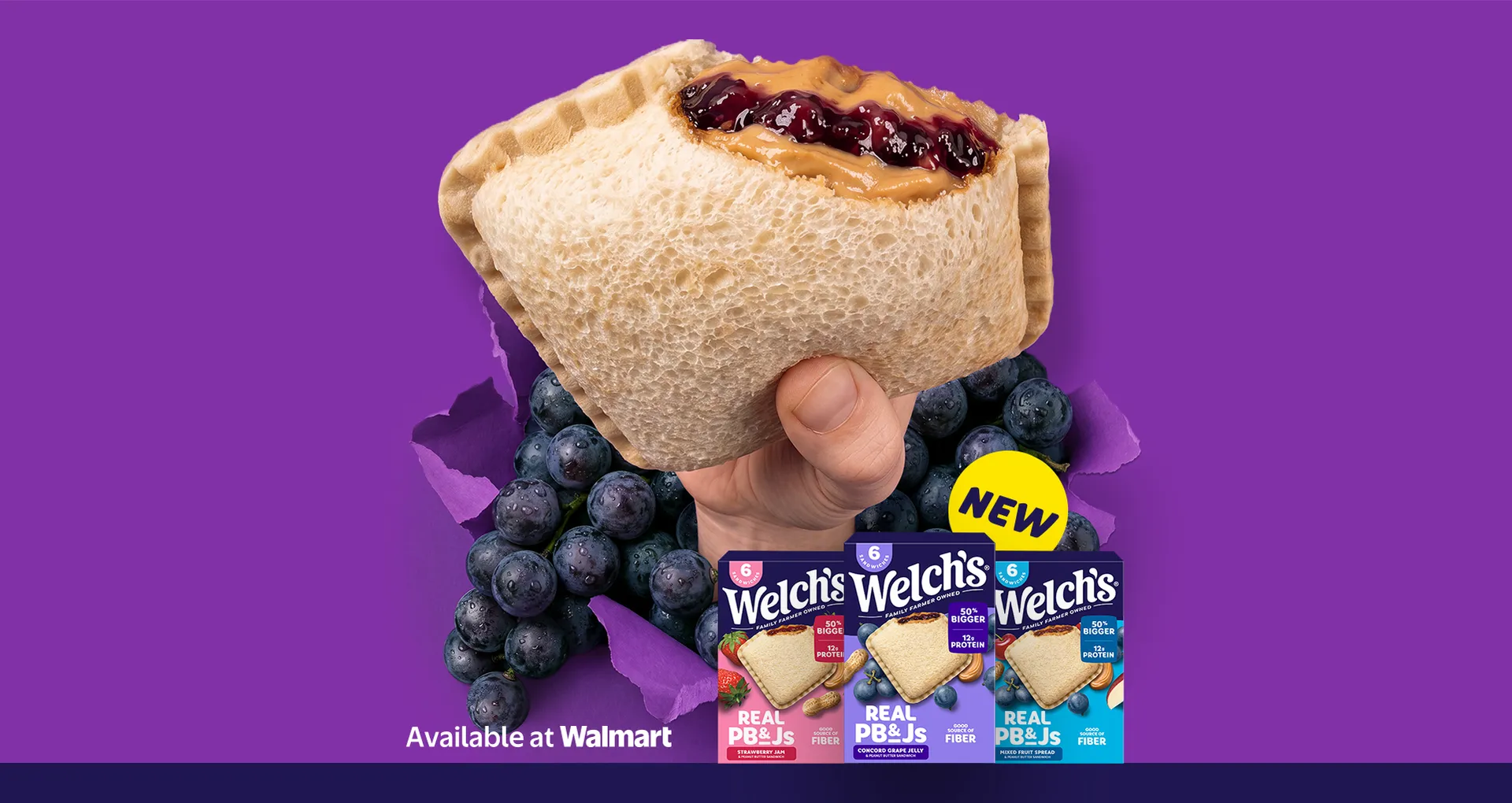 Peanut butter and jelly sandwich with grape filling held against a purple background, surrounded by grapes. Available at Walmart.