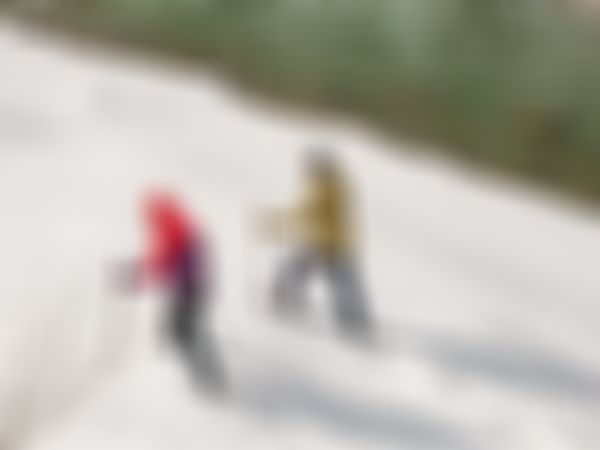 Zwei winterlich gekleidete Personen beim Wandern mit Schneeschuhen an einem Gewässer.