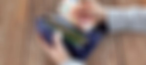 Hands holding a purple wallet filled with euro notes, counting two 50 euro bills, on a wooden table background.