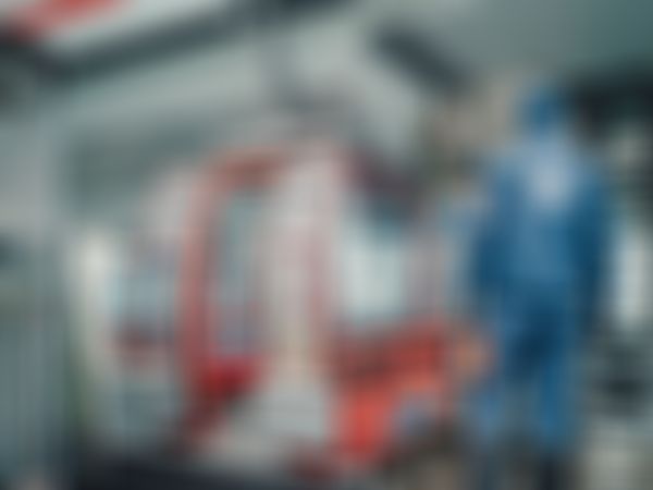 Ein Seilbahnbediensteter in blauer Uniform steht an einer Station neben roten Kabinen und bereitet sich auf die Fahrt bei verschneitem Wetter vor.