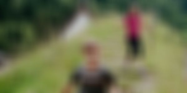 Kinder spielend auf einem Pfad der durch eine Wiese in einem Bergdorf führt.