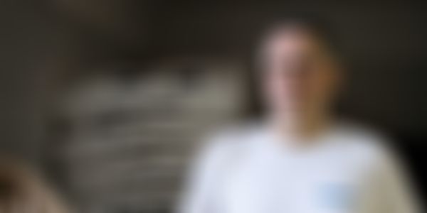 Mittelalter Mann in einem weissen T-Shirt der in einer Backstube vor Mehlsäcken steht.