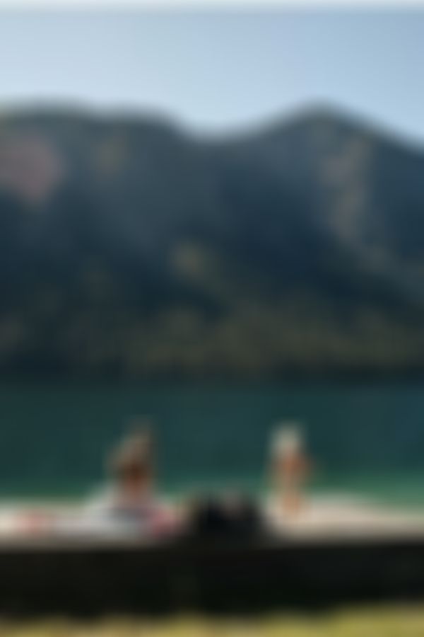 Frau mit kleinem Kind an einem tiefblauen, türkisen Bergsee mit alpiner Landschaft im Hintergrund.
