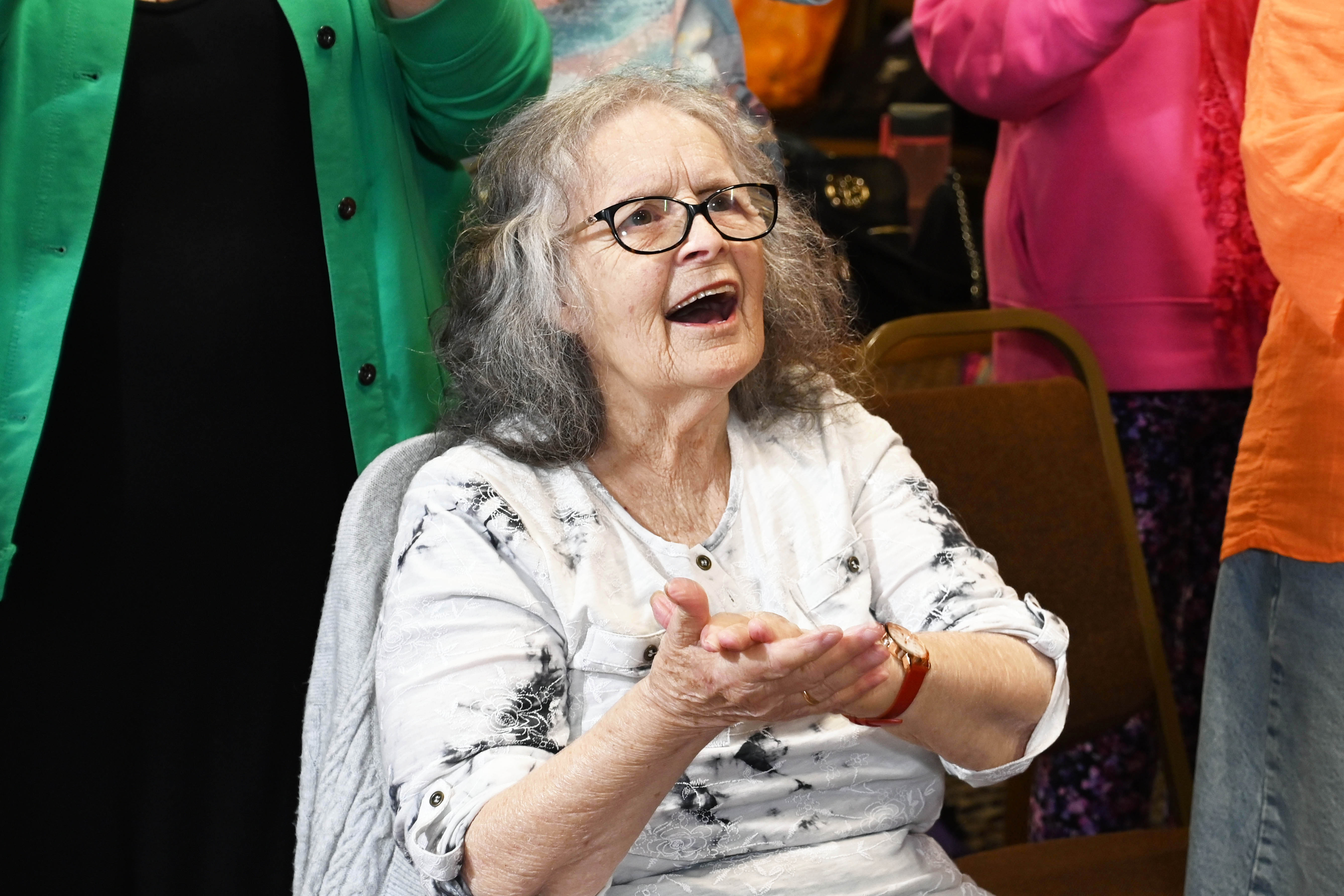 An older woman clapping hands in time with the music
