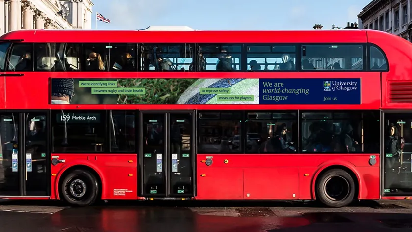 A red double-decker bus with an advertisement