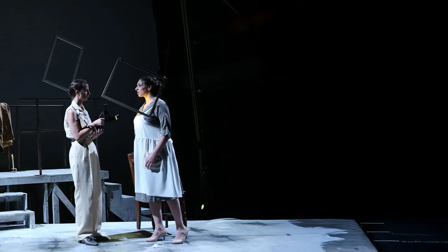 Two actors perform on a dimly lit stage