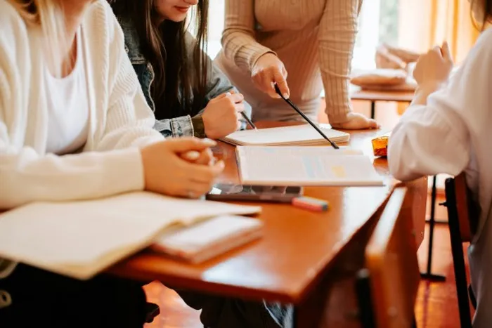 Students at a wooden desk with open books and notes
