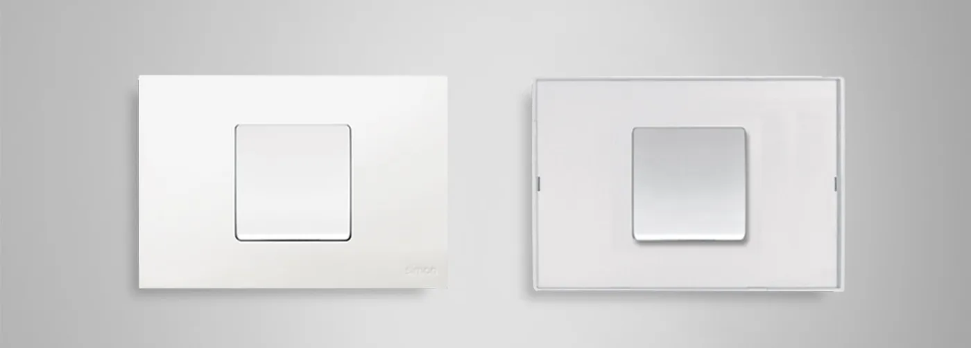 Dos placas Simon 27 Play: acabado blanco y acabado transparente sobre fondo gris.