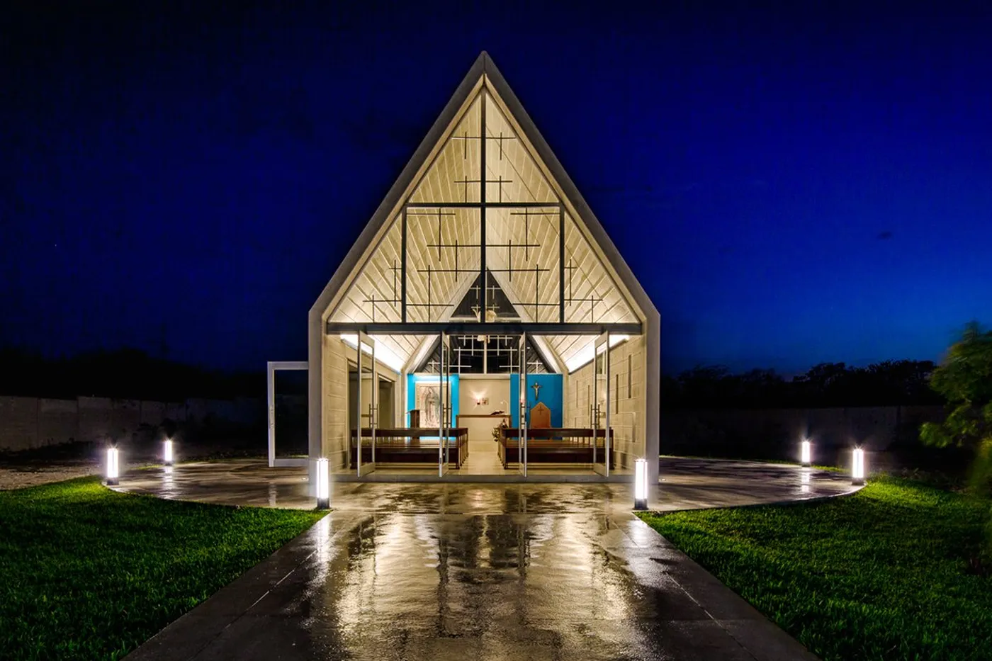 Capilla blanca iluminada de noche con 5 balizas Simon JR1 distribuidas en el atrio y los accesos.