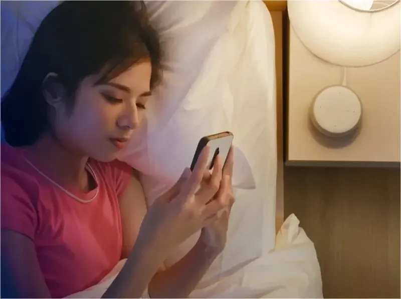 Simon iO smart home — user controls the lighting with the app from bed next to a Hub Pro on the bedside table