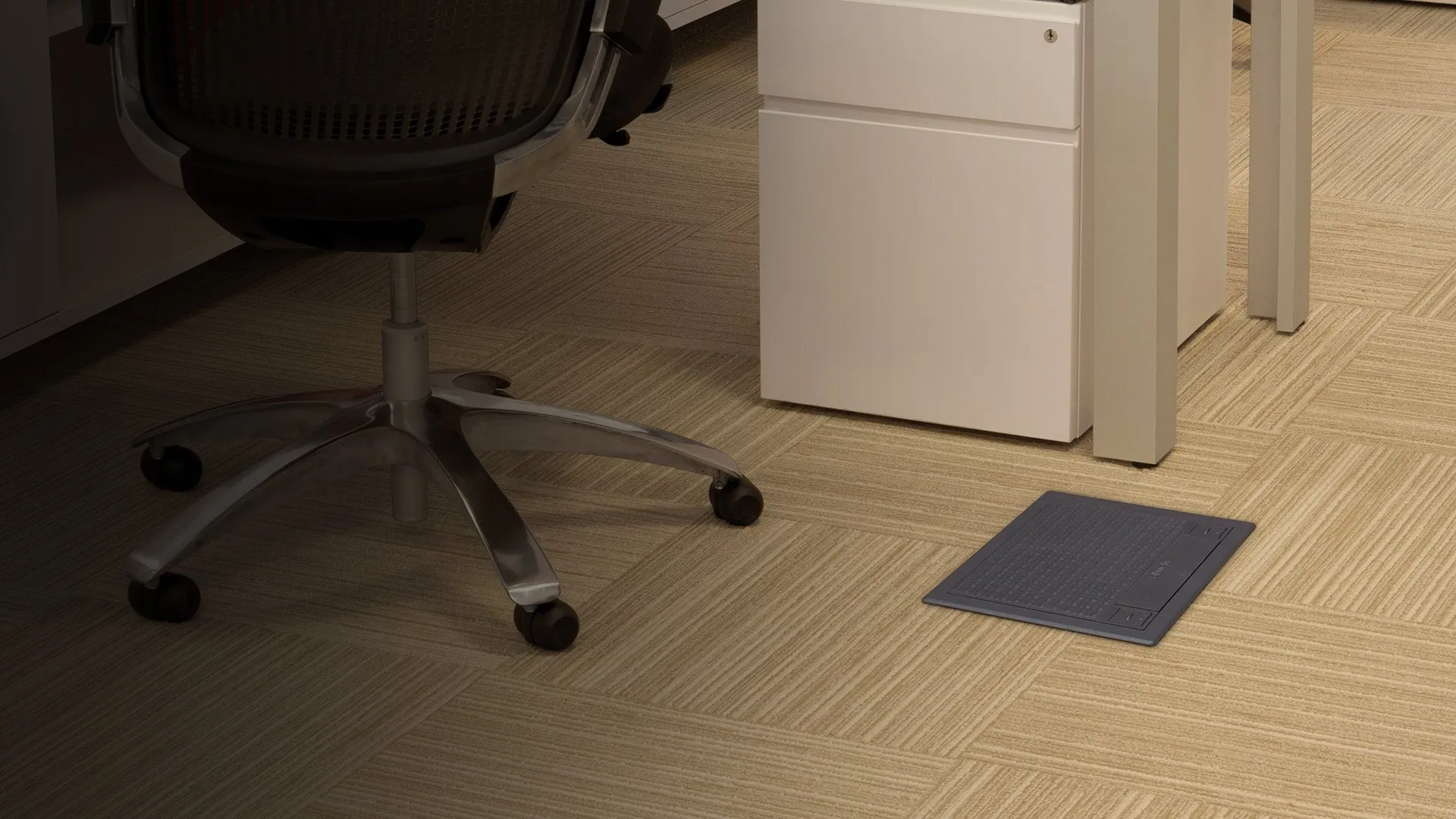 Ambiente de oficina con suelo de madera: silla de despacho sobre una caja de suelo Simon S instalada y conectada.