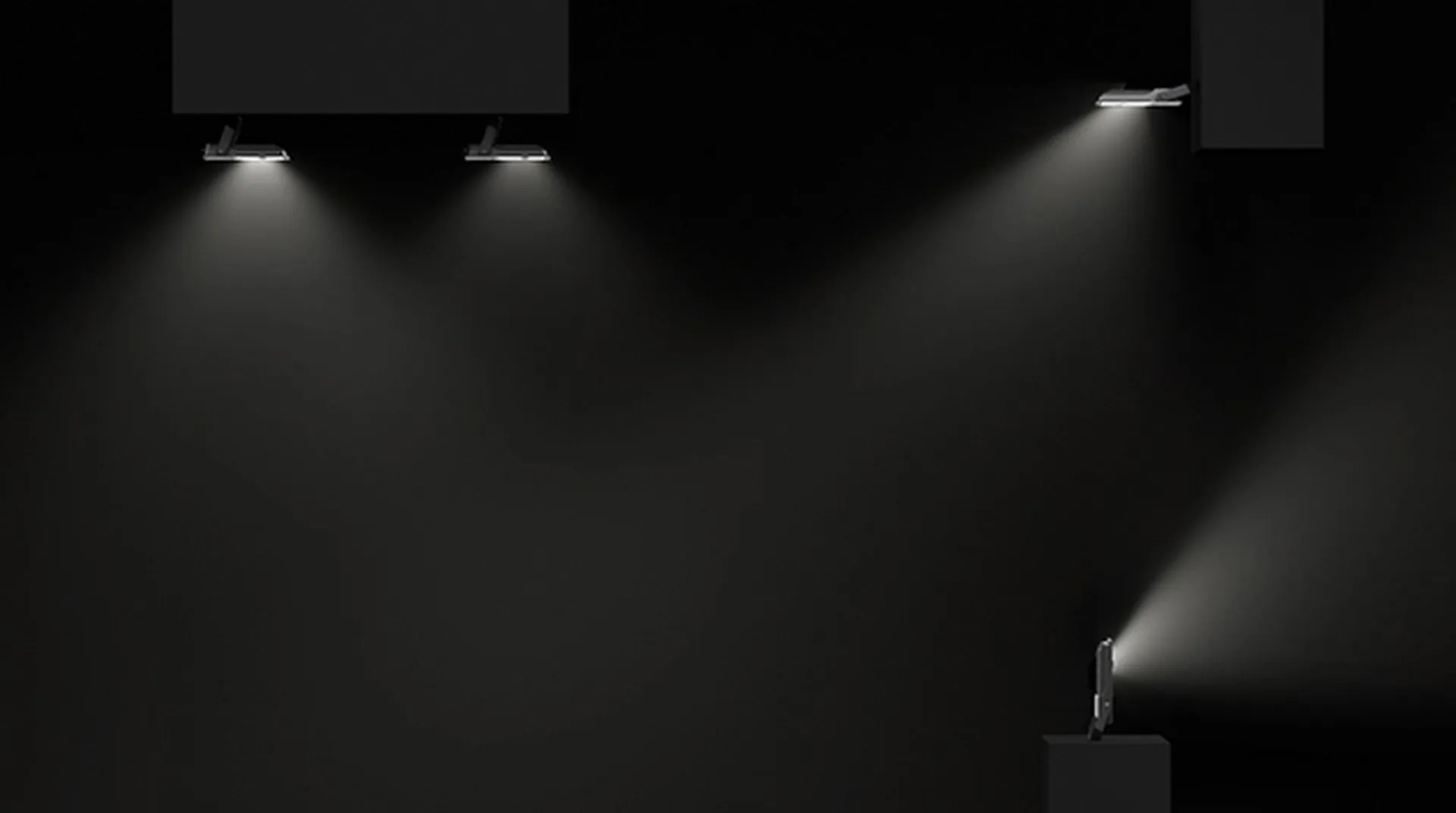 Several Simon 880 black industrial spotlights wall and ceiling mounted illuminating a dark space with directed light beams