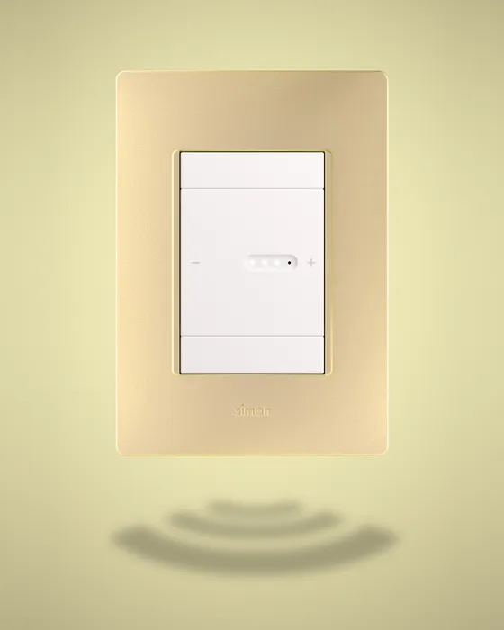 White Simon 26 iO switch on a gold frame against a warm yellow background, with decorative concentric waves underneath symbolising connectivity.