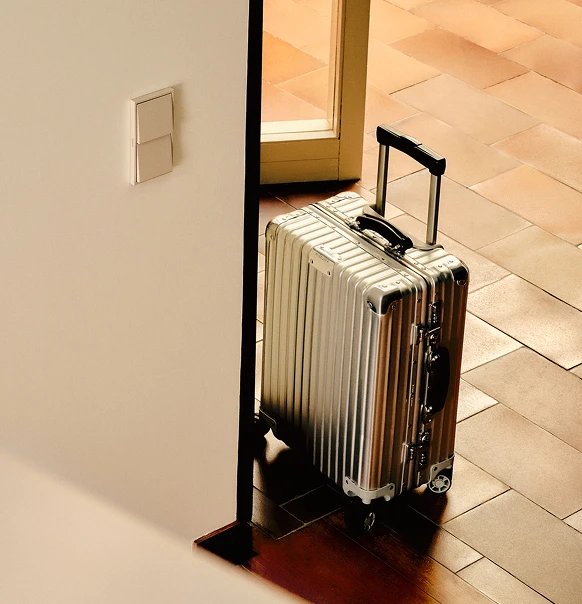 Simon 360 mechanism in Matte white in an entrance area with a silver suitcase and tiled floor