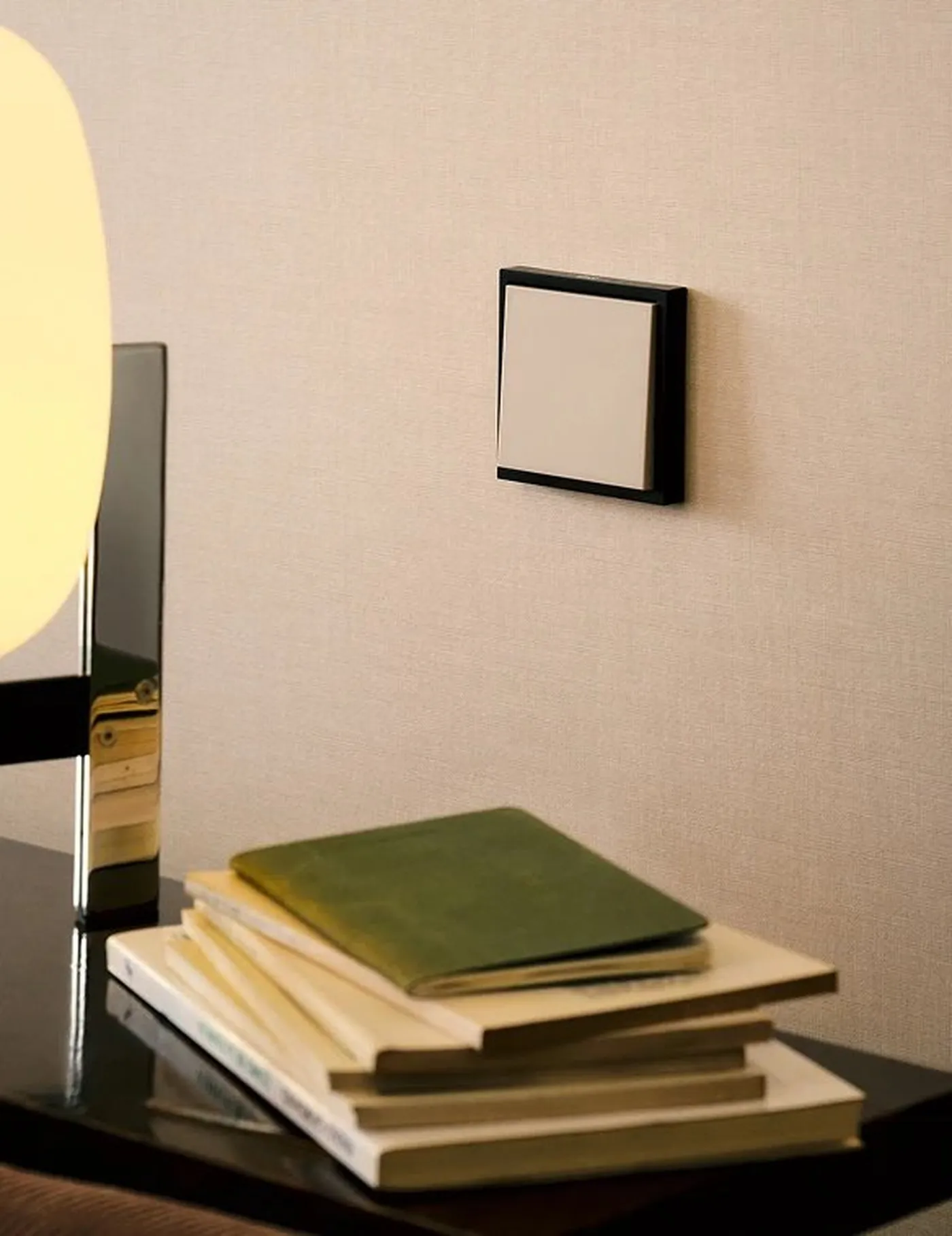 Mécanisme Simon 360 Combinaison S36 (bicolore) sur un mur crème avec lampe de table dorée et pile de livres