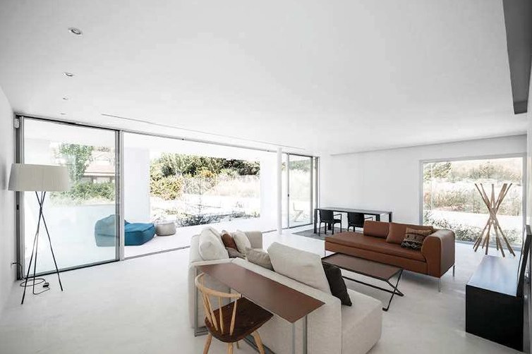 Open residential living room with sofa, table and garden views, lit with Simon 703 downlights