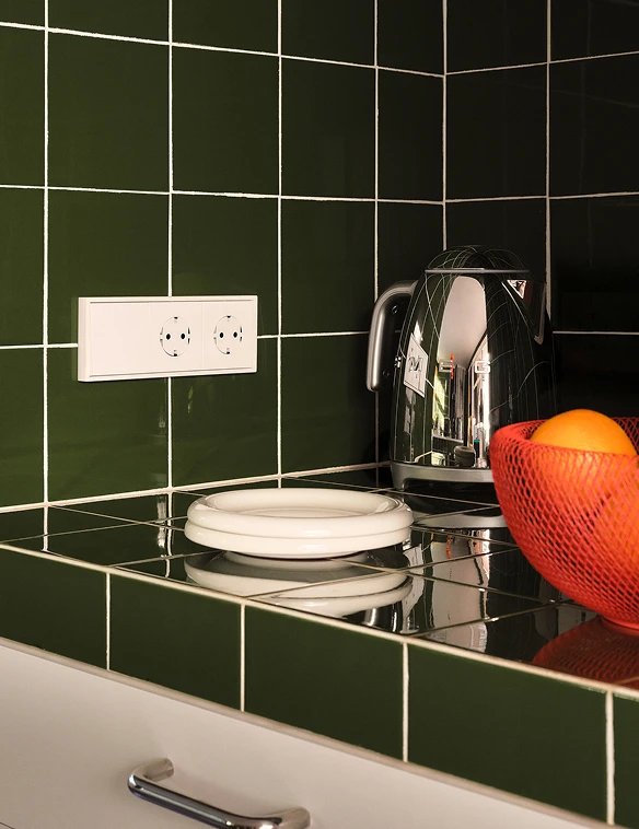 Simon 360 mechanism in Matte white in a kitchen with glazed green tiles, chrome teapot and a plate of fruit