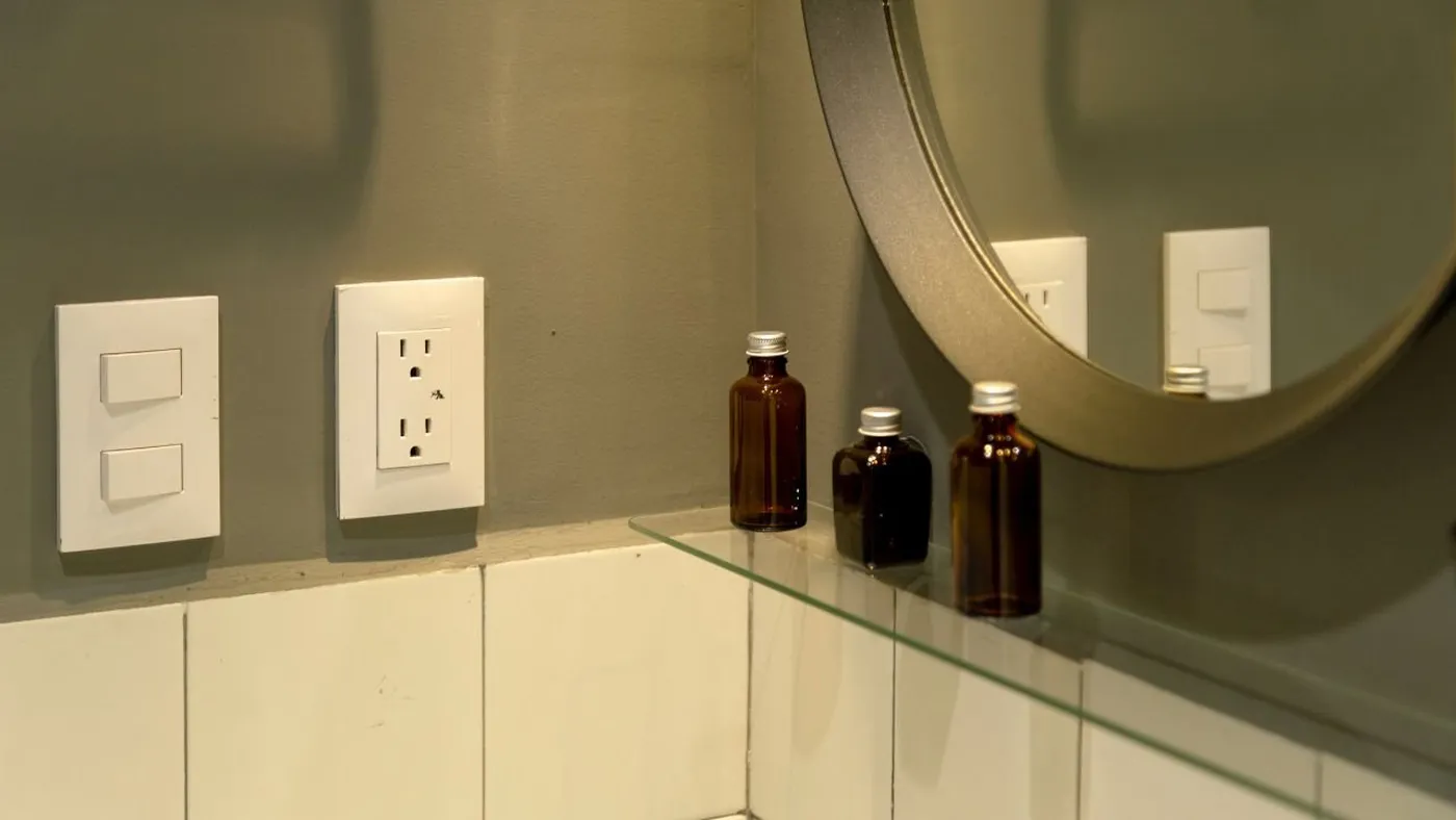 Simon 25 Plus switch in matt aluminium finish on a white gallery wall with decorative paintings.