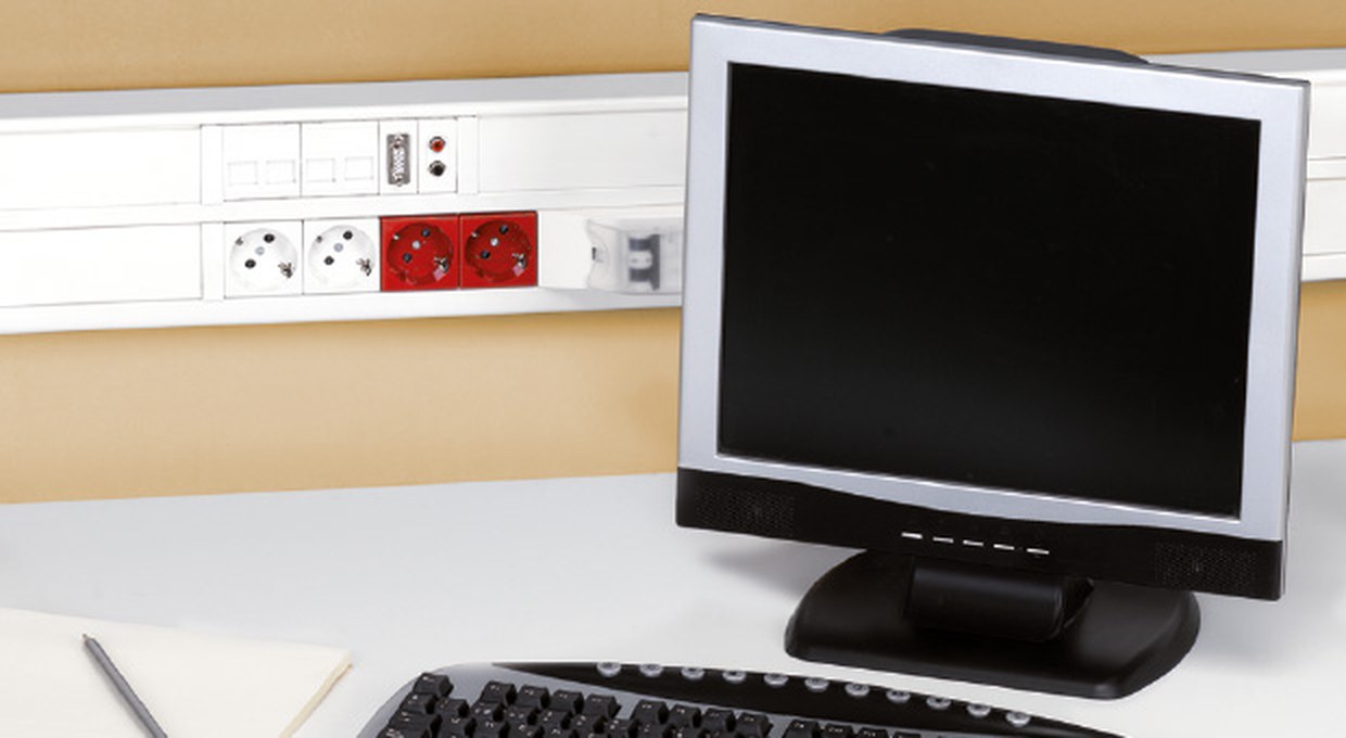 Calha K45 de PVC instalada em parede sobre secretária com monitor
