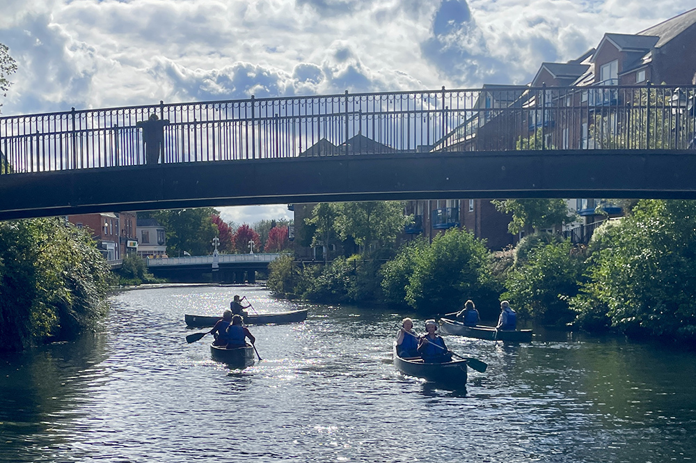 Listeners paddling canoes along the river