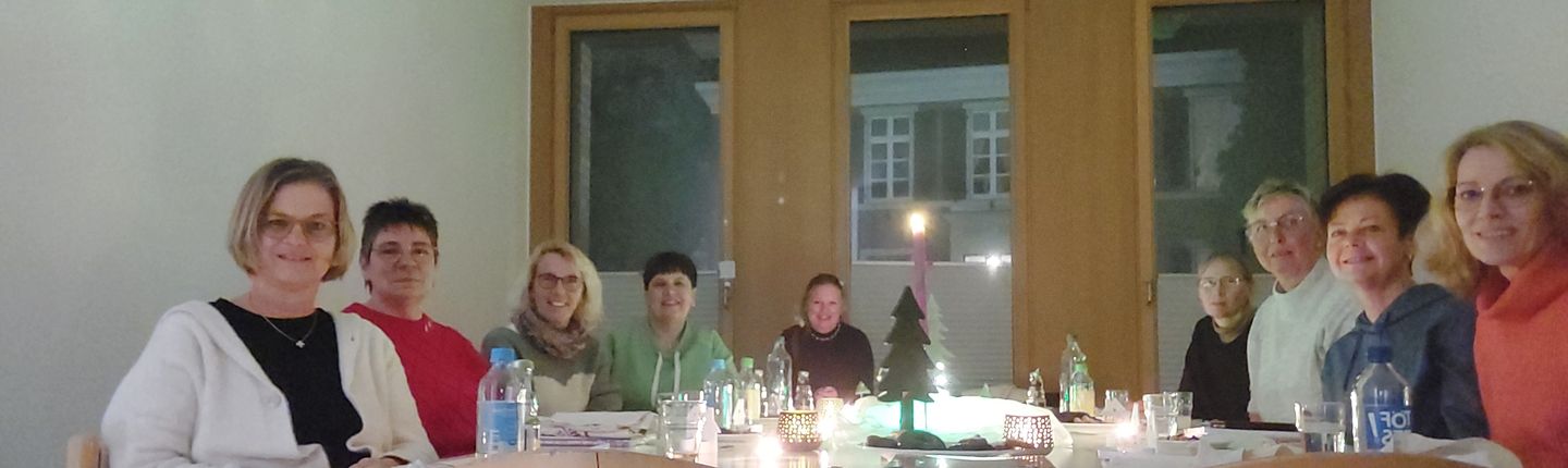 9 Frauen sitzen am Tisch, in der Mitte steht eine Kerze