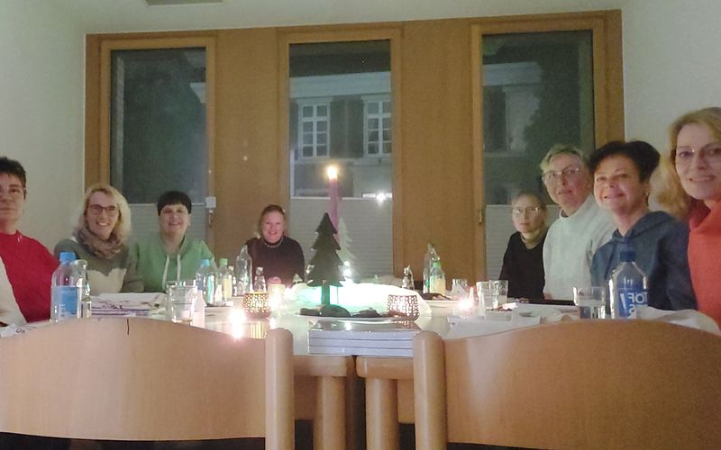 9 Frauen sitzen am Tisch, in der Mitte steht eine Kerze