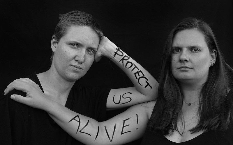 2 Frauen haben auf ihren Unterarmen Protect us alive geschrieben