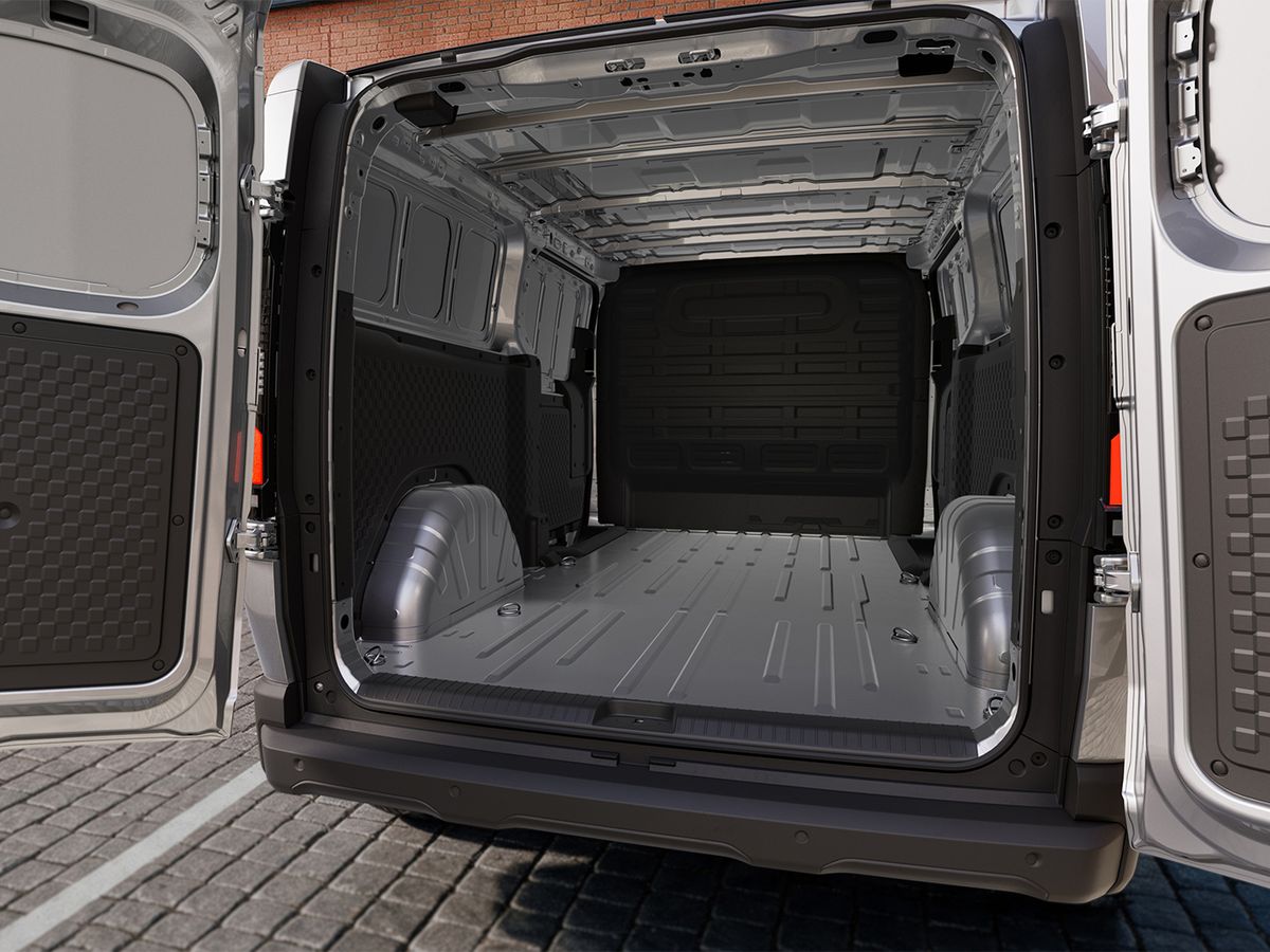 Open rear doors of an empty cargo van with a spacious metal interior and a textured floor, parked on cobblestone pavement.