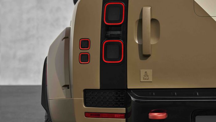 Close-up of a tan SUV's rear, showing distinctive square tail lights, a handle, and a Dakar badge on the side.