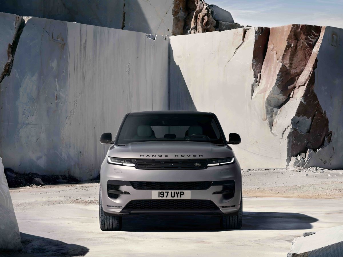 A silver Range Rover parked in an open stone quarry with large marble slabs and rough rocky terrain in the background.