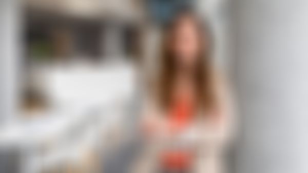 Frau lehnt an einer Säule in einem Büro und lächelt in die Kamera