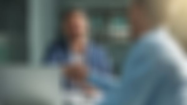 Zwei Geschäftsmänner sitzen am Schreibtisch und geben sich die Hände.